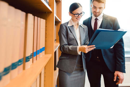 Lawyers in library of law firm discussing strategy in a case holding file