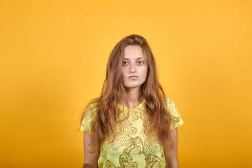 brunette girl in yellow t-shirt over isolated orange background shows emotions