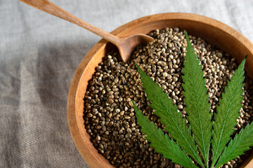 cannabis seeds in a wooden plate with a green leaf on top for food consumption
