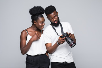 Young african couple looking at taked photo on photo camera standing isolated on white background