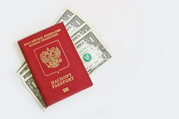 The Russian foreign passport lies on top of one-dollar bills on a light background. Traveling abroad, budget vacation.