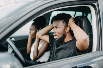 Young african shocked look couple driving car on high speed on the road