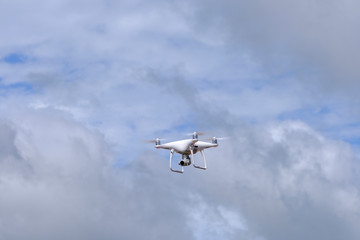 White drone quadcopter flying on the air for take a photo and video with white cloudy background.