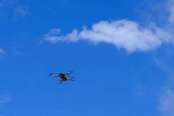 Black drone quadcopter flying on the air for take a photo and video with blue sky background.