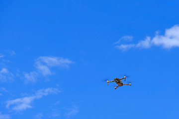 Black drone quadcopter flying on the air for take a photo and video with blue sky background.