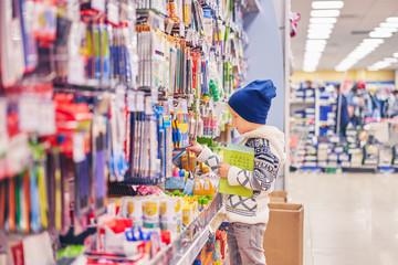 boy chooses pens for school. the child in the store selects the goods.