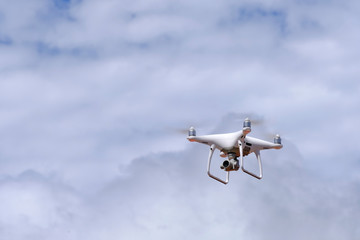 White drone quadcopter flying on the air for take a photo and video with white cloudy background.