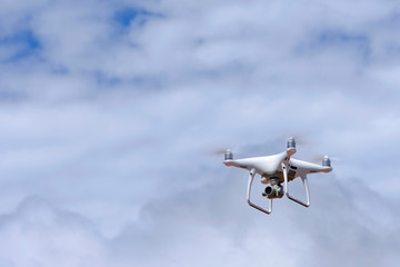 White drone quadcopter flying on the air for take a photo and video with white cloudy background.