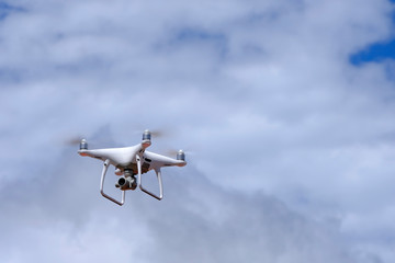 White drone quadcopter flying on the air for take a photo and video with white cloudy background.