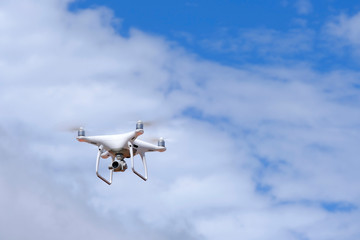 White drone quadcopter flying on the air for take a photo and video with white cloudy background.