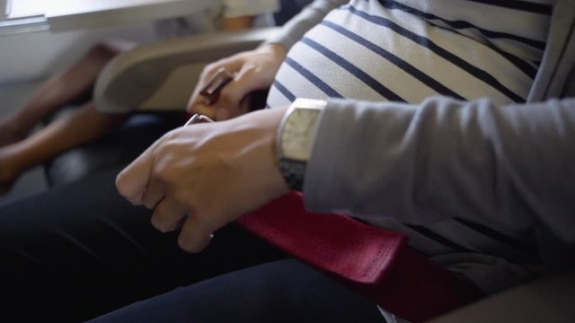 Happy pregnant mother enjoy safety flight fasten seat belt