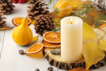 Candles, cones and decorative pumpkins and autumn yellow leaves on a white wooden table. autumn composition. comfort. decor