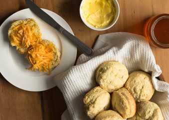 Baked scones, cheese, honey and butter on rustic table - top view photo of home made biscuits