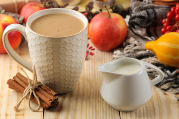 Hot autumn drink, coffee or cocoa, with yellow leaves and decorative pumpkins, acorns and apples on a natural wooden table. autumn composition.