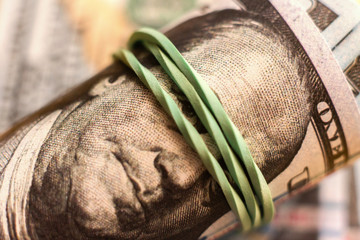 close up macro of paper currency roll of hundred dollars knitted by a rubber band