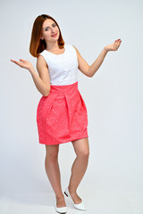 Full-length vertical portrait of a brunette girl with beautiful brown hair in a pink and white dress on a white background. He stands in different poses, demonstrates emotions.