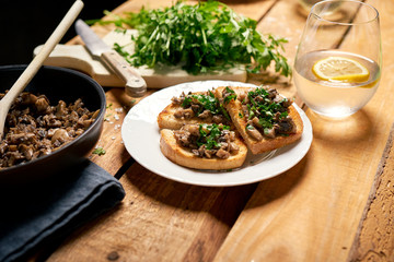 Toasts with mushrooms on white plate on wooden kitchen table