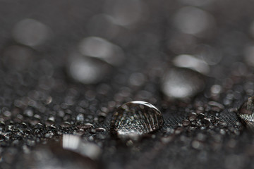 Rain water droplets on a black waterproof fabric