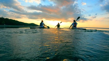 Group of people are canoeing along the sunset waters