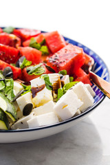Colorful turmeric chickpea watermelon salad with feta cheese, tomatoes, zucchini, mint and balsamic vinegar on marble table. Summer fresh easy lunch