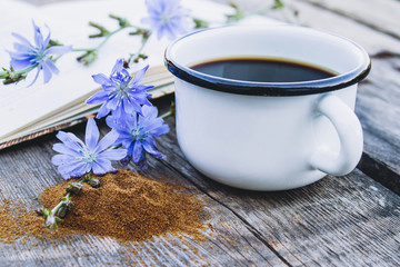 White cup with chicory drink and flowers near chicory powder. Tea from chicory. Healthy eating concept.