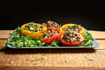 Peppers stuffed with champignons with lettuce on wooden table