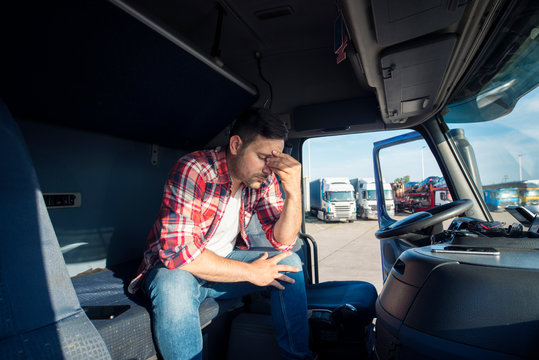 Truck driver sitting in his truck cabin feeling worried and upset. Truck driver lifestyle and problems.