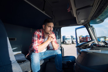 Truck driver sitting in his cabin and thinking about his family. Trucker missing his family being...