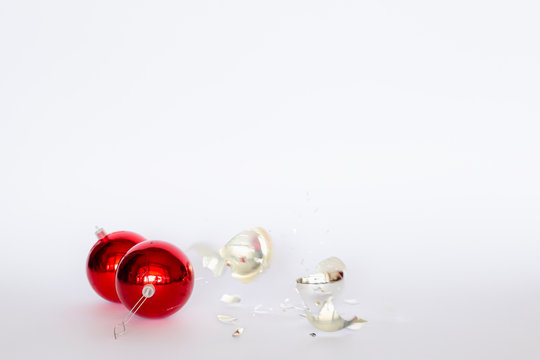 Falling and broken red and silver Christmas baubles on white background