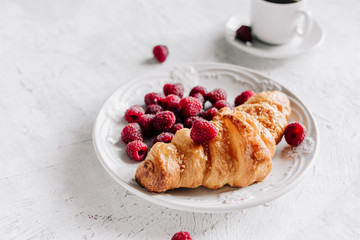 Croissant with raspberries on a plate and a cup of coffee
