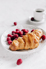  Croissant with raspberries on a plate and a cup of coffee
