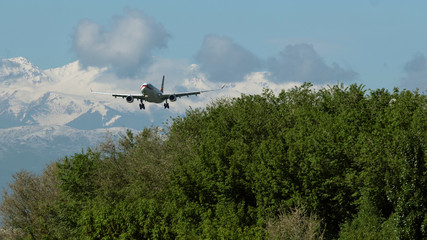 Obraz na płótnie Canvas Wide body twin engine commercial airplane approaching to landing against picturesque snowy mountains at the background