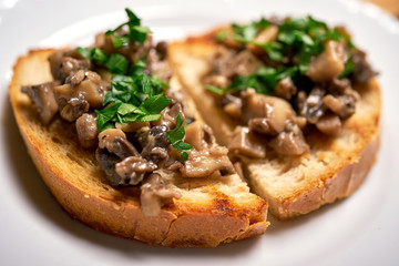 Close up of toasts with mushrooms on wooden kitchen table