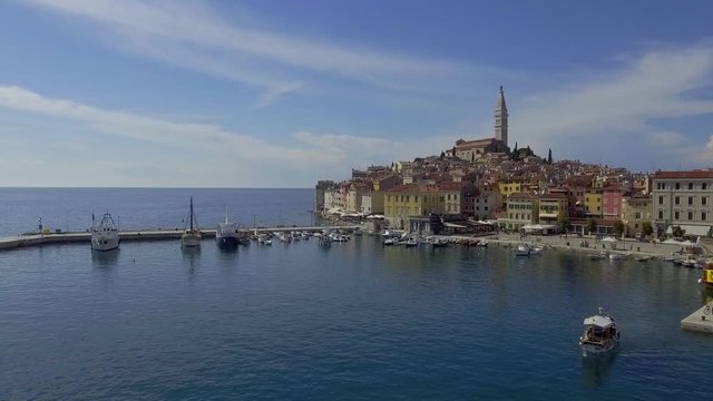 Aerial drone approaching shot as flying to the old city of Rovini over the port. Historical European tourist destination on a bright sunny day.