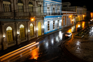 Fototapeta na wymiar Night on a Cuban street after the rain with lights and moving cars