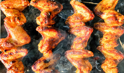 Delicious juicy grilled chicken wings outdoors in smoke. BBQ Chicken Cooking Process