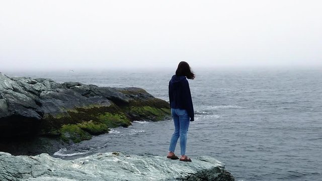 lonely girl walks sea shore to cliff edge slow motion