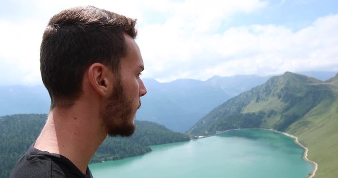 Man eating chocolate on top of a mountain in Switzerland, with stunning view towards Lake Ritom.