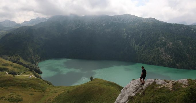Backpacker enjoying the view towards the famous Lake Ritom in Switzerland.