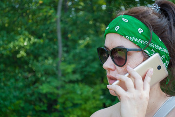 Serious stressed girl speaking on cellphone in park. Frowning young woman in casual calling on mobile phone, listening and staring into distance. Serious phone talk concept