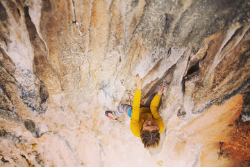 Climber overcomes challenging climbing route. A girl climbs a rock. Woman engaged in extreme sport. Extreme hobby.