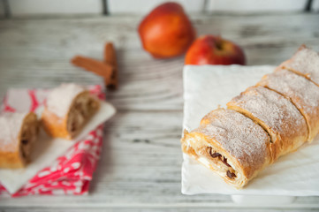 Apple strudel with apples, cinnamon closeup and copy space. Thanksgiving Meal Concept. Apple pie with icing sugar in a cut and whole.
