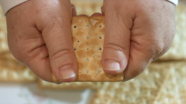 Close up of Female hands breaking a cracker in half. Macro 4K