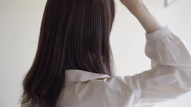 Back view of woman unraveling her hair with a brush