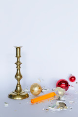 Obraz na płótnie Canvas Front view of falling and shattered red and silver Christmas baubles and a bronze candleholder with a yellow candle on white background