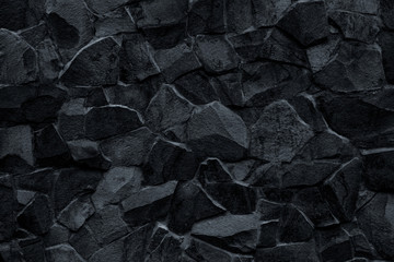 Black stone wall background. Mosaic of bricks in retro style, modern. Dark rock texture, brick wall pattern. Gray grunge surface. Marble geometric facade building details.