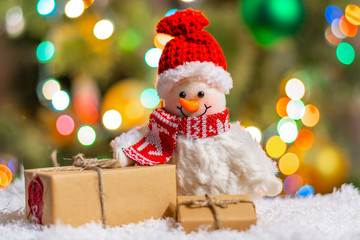 Holiday, New Year's Eve, Christmas background for congratulations, banner, postcards, advertising with a place for text. Snowman and boxes with gifts on a bokeh background. Copy space, front view.