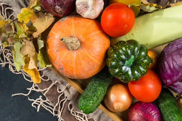 Fototapeta na wymiar lots of autumn fresh vegetables, pumpkins, tomatoes, cabbage, zucchini, onions, dry fallen leaves, cucumber, garlic, top view