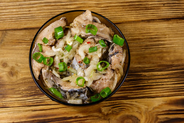 Marinated carp in glass bowl on wooden table. Top view
