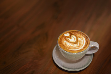 ..Mocha coffee mug with heart-shaped whipped cream placed on a dark wooden desk and shining with warm tones.
